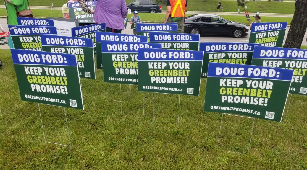 A garden of blue and green lawn signs with white text reading: Doug Ford: Keep your Greenbelt Promise!