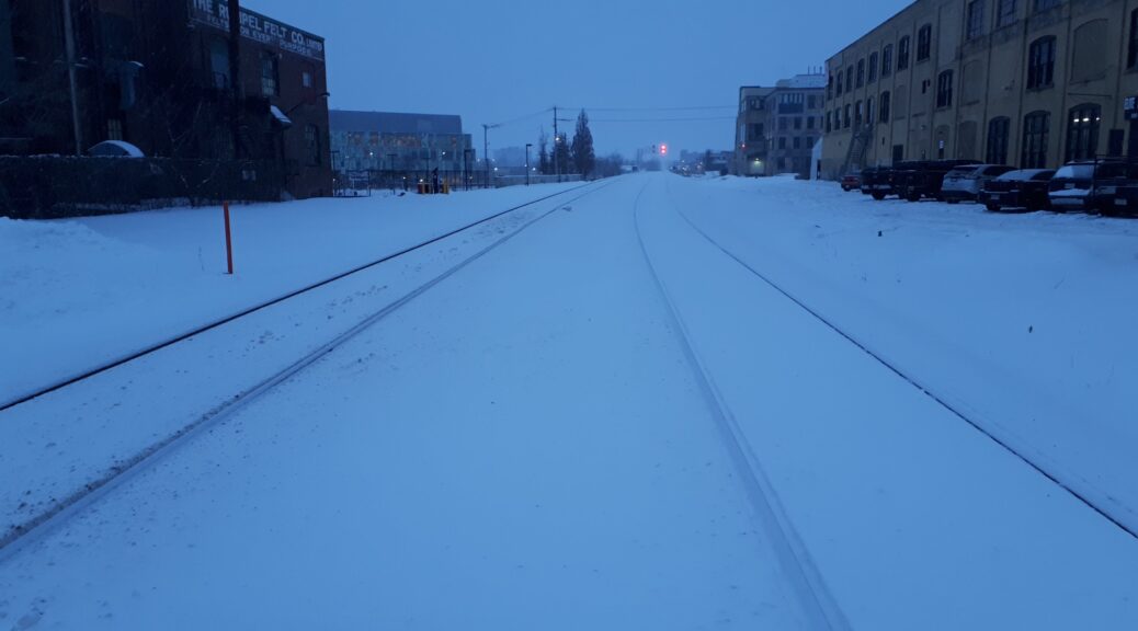 A picture looking south down the GO Train tracks on Duke Street in Kitchener. Tow of the tracks are visible although snow is covering the tracks but a train has recently passed because the tracks are clean