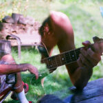 (double exposure of a man sitting in the grass playing a guitar)