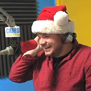 Brian Chris at the microphone and wearing a Santa hat