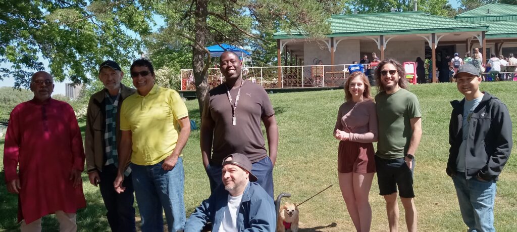 People posing for a group photo, one with a dog on a leash, one in a wheelchair