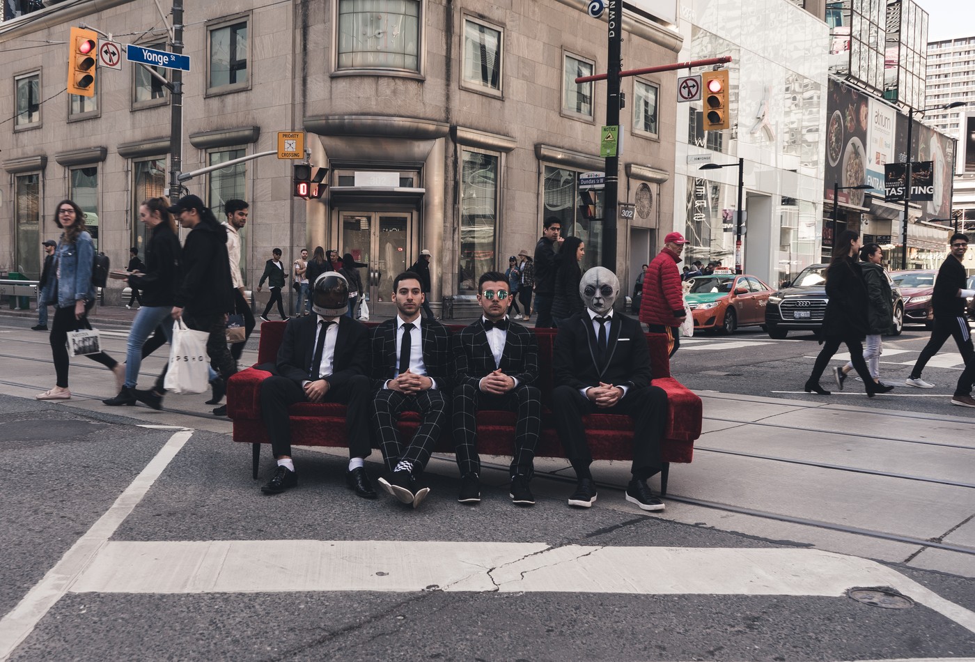 Four people sitting on a couch in the intersection of Dundas and Yonge Streets in Toronto