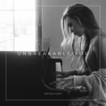 Unbreakable | single | Natalia Zuk (B&W photo of a woman playing piano)