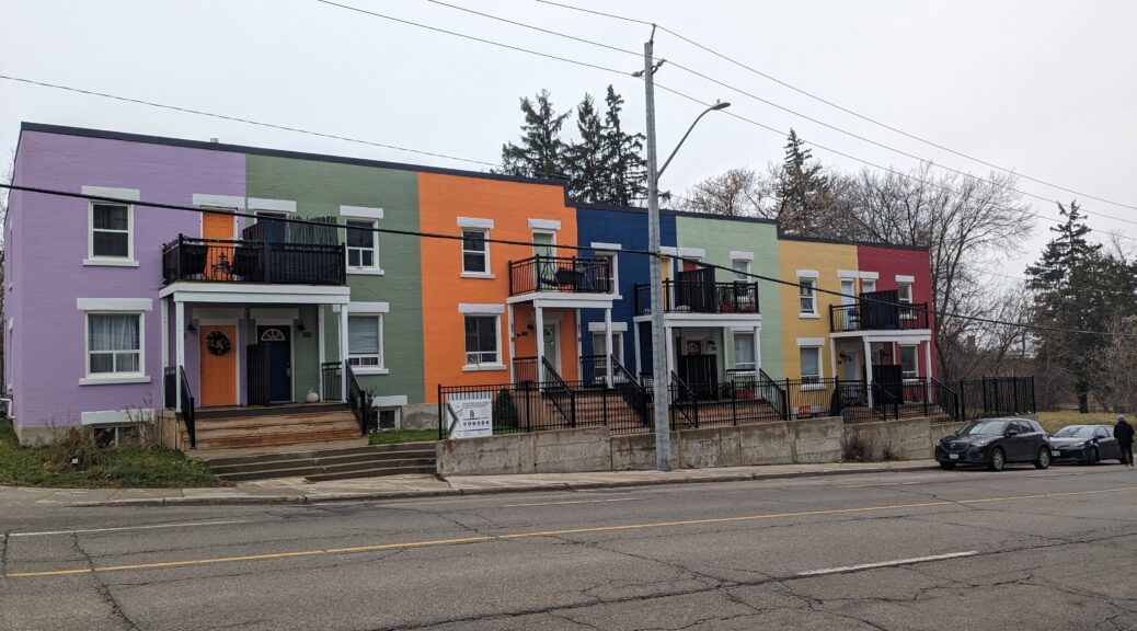 A row of seven brightly coloured townhouses at 93-99 Benton St in Kitchener are slated for demolition. The block of townhouses have been named 'Rainbow Row' due to the 7 different colours. The residents of these townhouses are currently paying less than market rent and, faced with eviction, are pleading with city council to reject the developer's proposal.