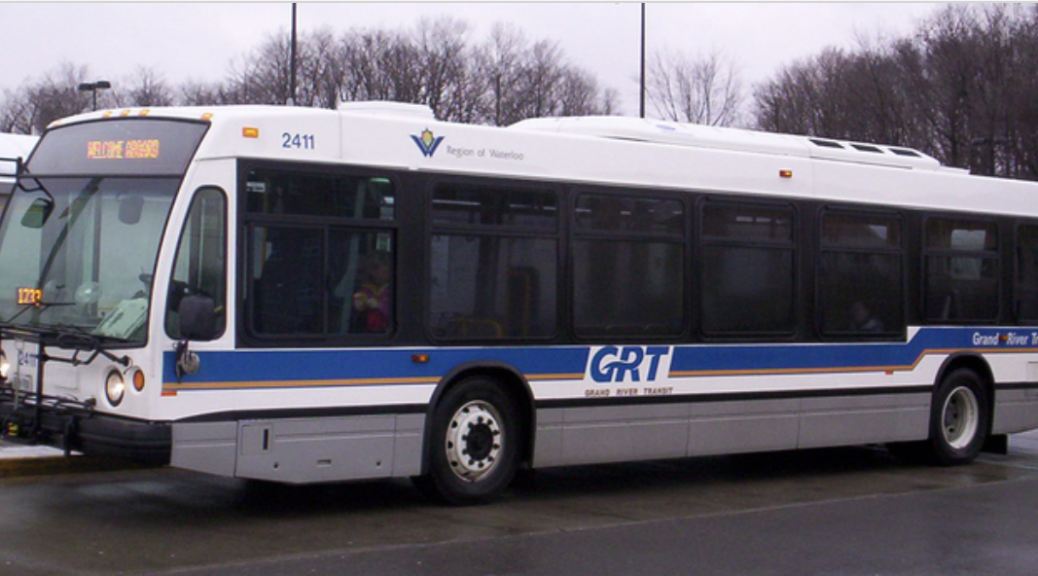 A Grand River Transit bus sits parked beside a bus stop on a winter morning