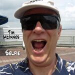 Tim McInnes | Selfie (headshot of Tim McInnes laughing, wearing a baseball cap and sunglasses)