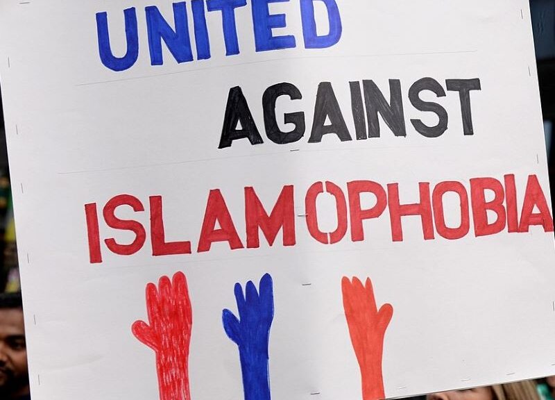 A poster from a demo reading "United Against Islamophobia" with three hands reaching up from the bottom of the poster.