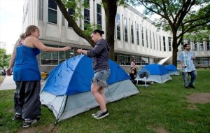 People setting up tents in front of a large white building the Region bought for the police to grow into.